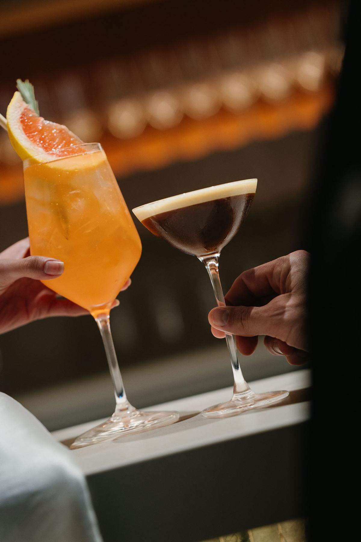 Two cocktails being raised at the bar