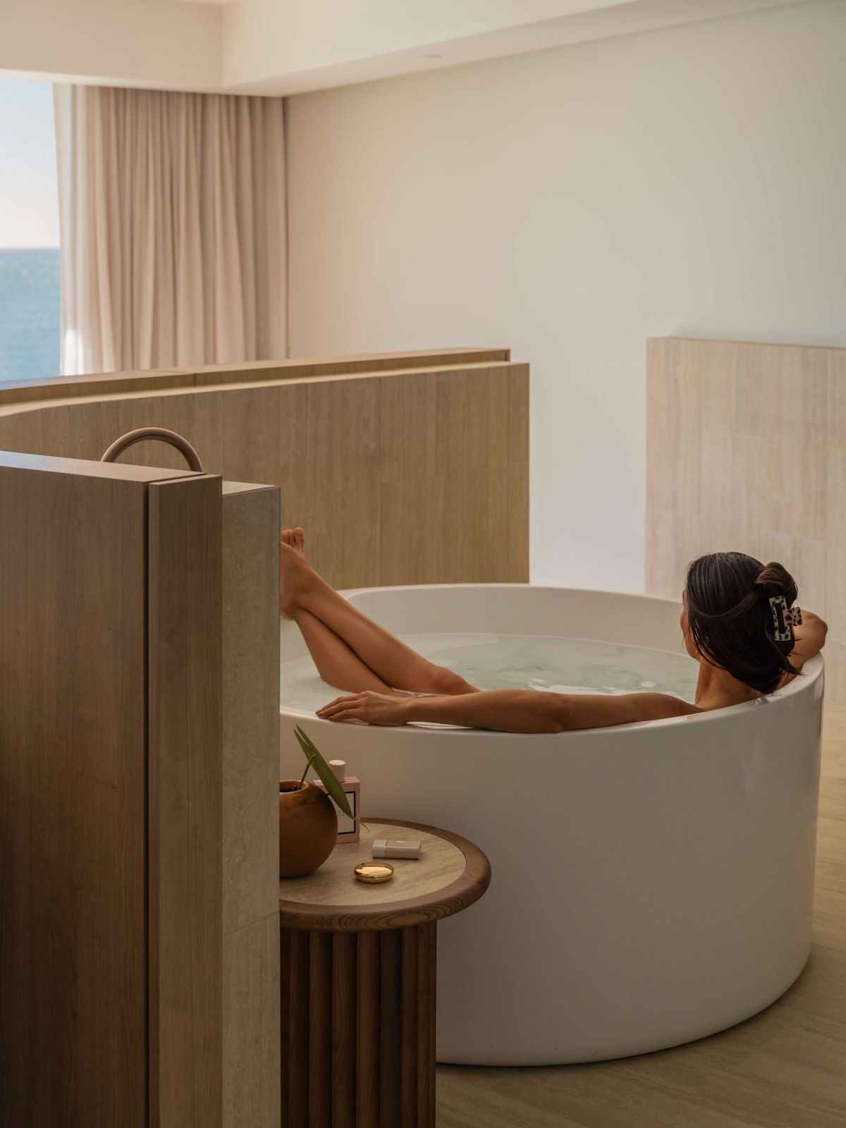 A guest relaxing in a round freestanding bath in a suite